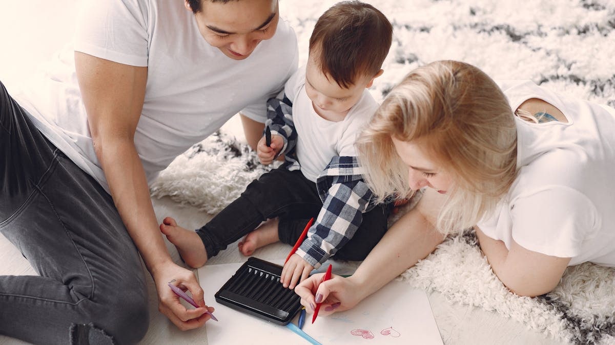 Parents and child enjoying drawing together on the floor, creating memories.